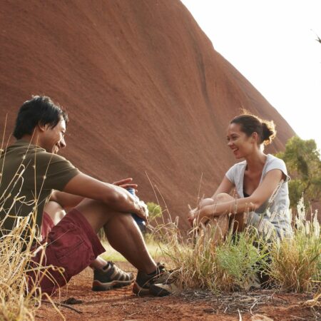 Couple sitting at Uluru on our Northern Territory tours. 4 day uluru tour from alice springs