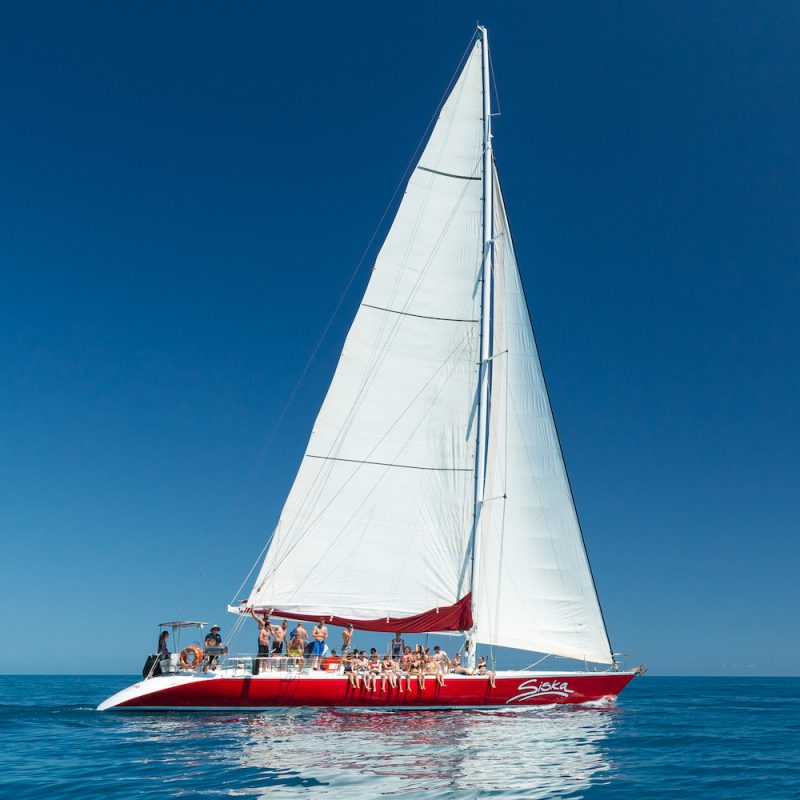 A beautiful sailing boat in the turquoise waters of the Whitsundays, surrounded by lush tropical islands. Perfect for a 2 day 1 night adventure!