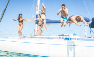 Must See East Coast Australia Group of friends jumping from the boat. having fun on the yacht and in the water on our small group sailing whitsundays adventures