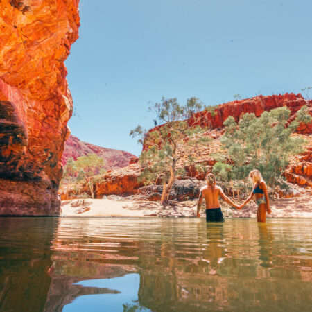Real Aussie Adventures, Small Group Adventure Tours Australia. A couple taking a dip at the Ormiston Gorge. On our 4 day uluru tour from alice springs