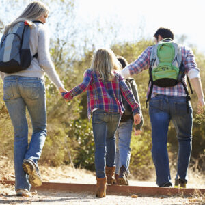 Rear View Of Family Hiking In Countryside Wearing Backpacks