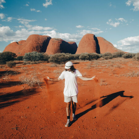 Real Aussie Adventures, Small Group Adventure Tours Australia. Like sand through the hour glass, sand slips through Sailor Sam's hands at Kata Tjuta. Australia's Red Centre is home to natural wonder and cultural landmark, Kata Tjuta (The Olgas). Hike around the soaring rock domes, which glow at sunrise and sunset. Located approximately 40km west of Uluru, the ochre-coloured shapes are an intriguing and mesmerising sight.