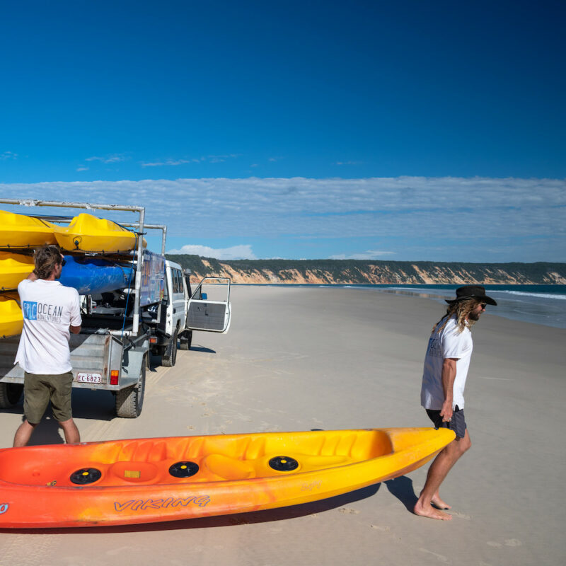 Real Aussie Adventures, Small Group Adventure Tours Australia. Man dragging Kayak on the beach. Dolphin View Kayak Tour from Noosa.