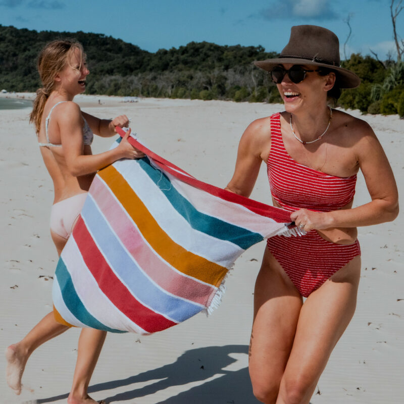 Real Aussie Adventures, Small Group Adventure Tours Australia. Girls playing with a towel on the beach. Relaxing on Whitehaven Beach sailing the Whitsundays