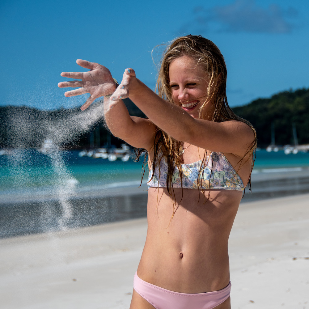 Real Aussie Adventures, Small Group Adventure Tours Australia. Girl playing in the sand on Whitehaven Beach on our Whitsunday Boat Tours