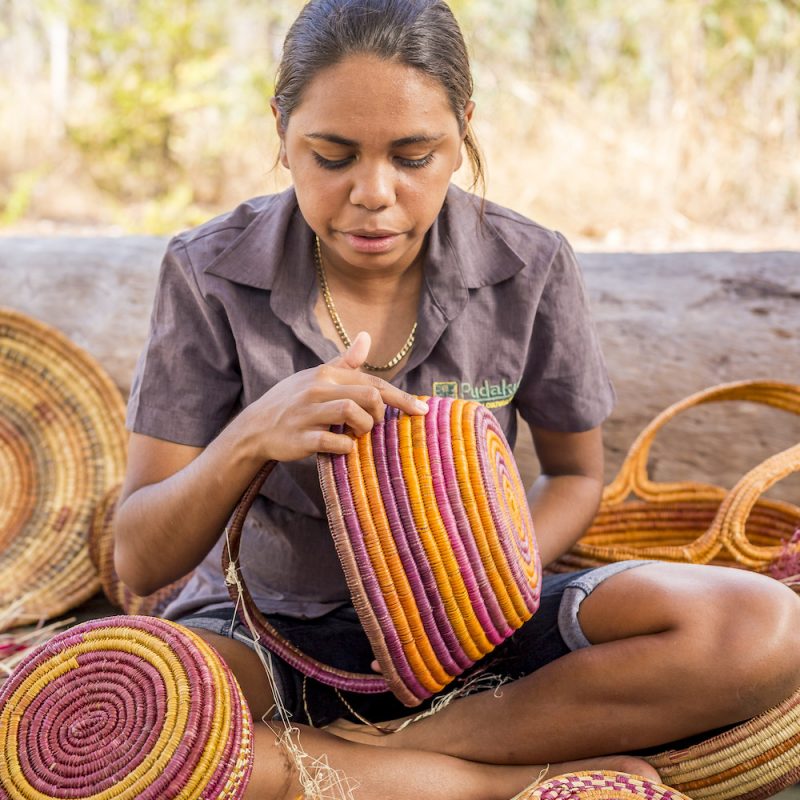 A guide speaks about basket weaving and Aboriginal culture on a Pudakul Aboriginal Cultural Tour.Pudakul Aboriginal Cultural Tours is Aboriginal owned and operated with the majority of their tours taking place from the Adelaide River, on Aboriginal owned and managed lands. Guests are taught and shown traditional techniques, such as clap stick and didgeridoo playing, spear making and throwing, dilly bag and basket weaving, plus guided walks and talks.